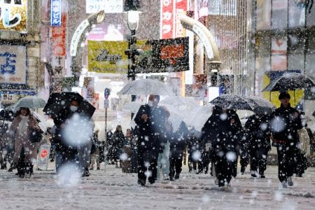 　雪が降る東京・渋谷のスクランブル交差点を歩く人たち＝５日夜