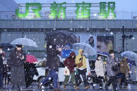 　雪が降る中、ＪＲ新宿駅前を歩く人たち＝５日午後