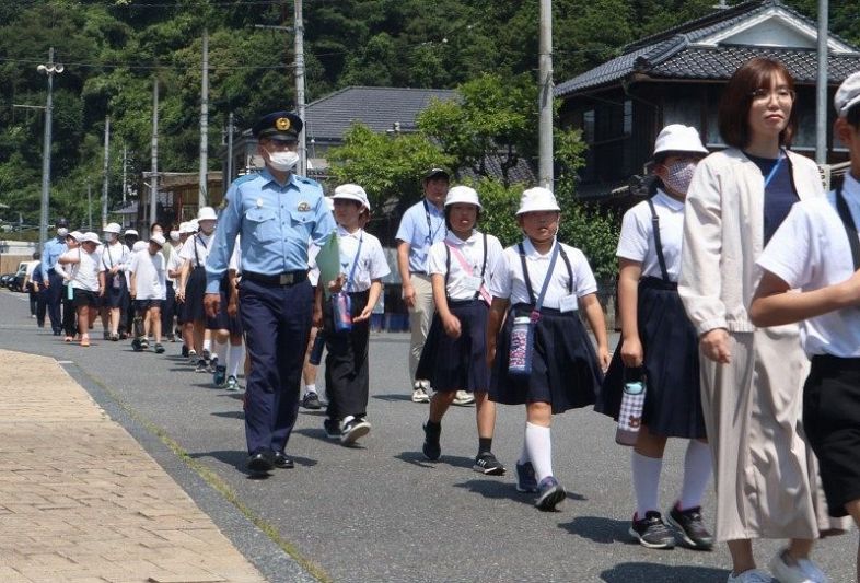 警官らの誘導で経路を確認しながら避難訓練する児童たち