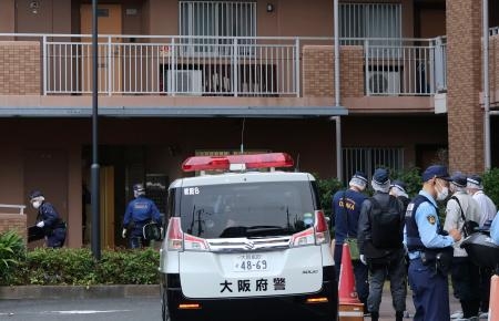 　１１０番通報があった集合住宅に出入りする警察官ら＝２６日午後６時１８分、大阪府吹田市