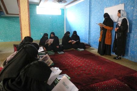 　アフガニスタンの首都カブールの「地下学校」で中村哲さんを題材にした絵本を読む女子生徒ら＝１１月（共同）