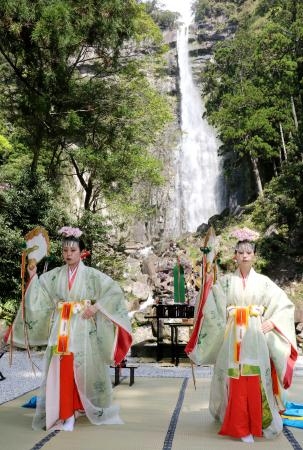 　熊野那智大社の「桜花祭」で、舞を披露する巫女。奥は那智の滝＝１４日午前、和歌山県那智勝浦町