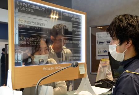 　透明ディスプレーを使ってコミュニケーションを取る外国人観光客（左）＝２６日午後、北海道千歳市