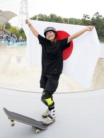 　杭州アジア大会のスケートボードパーク女子で金メダル獲得を決め、日の丸を掲げる草木ひなの＝２５日、中国・杭州（共同）