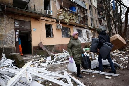 　ロシア軍のミサイル攻撃を受けた病院近くで、損傷したアパートから家財道具を運び出す住民ら＝２９日、ウクライナ東部ドニプロ（ロイター＝共同）