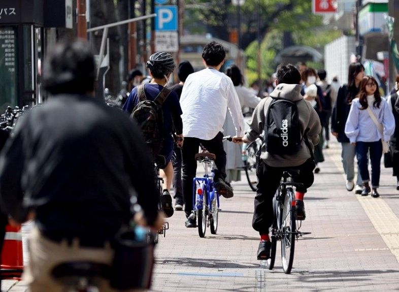 街中を行き交う自転車。改正道交法施行の初日、ヘルメットをかぶった人は少なかった＝岡山市北区駅前町