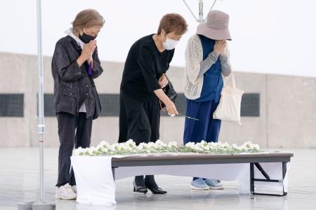 　北海道南西沖地震から３０年となり、慰霊碑前に設置された献花台で献花する人たち＝１２日午後、北海道奥尻町