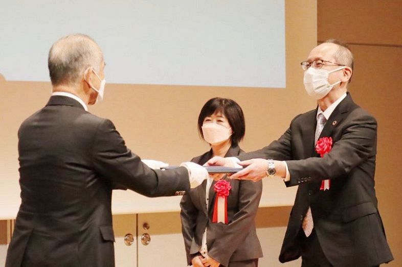 松田座長から表彰状を受け取る受賞団体の代表者（右）