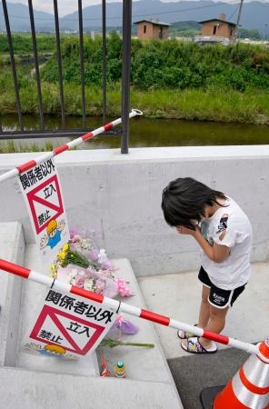 　小学生３人が溺れて死亡した現場付近で、手を合わせる同級生＝２２日午前、福岡県宮若市
