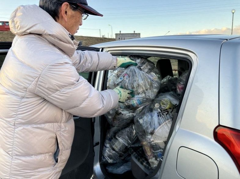 河川敷付近でプラスチック類を中心にごみを回収し、自分の車に積み込むボランティア