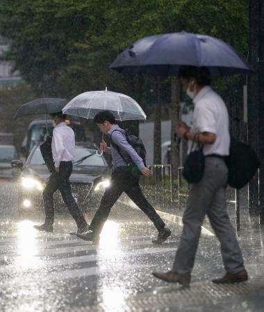 　雨の中、通勤する人ら＝８日午前、ＪＲ東京駅前