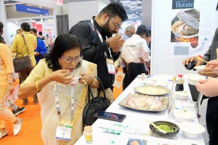 　インドの首都ニューデリーで開かれた食品展示会で、日本産のホタテやハマチの刺し身を試食する人たち＝３日（ＮＮＡ＝共同）
