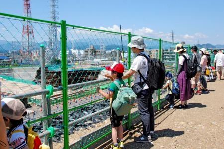 　リニア中央新幹線神奈川県駅（仮称）の工事の様子を見学する人たち＝１７日午前、相模原市