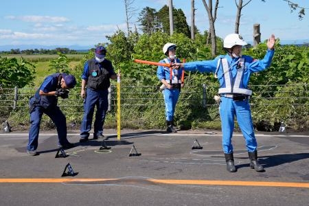 　トラックとバスが衝突した事故現場を調べる捜査員ら＝１９日、北海道八雲町