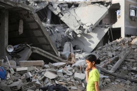 　パレスチナ自治区ガザ南部ラファで、イスラエルの攻撃で壊れた建物のそばを歩く少女＝２５日（ロイター＝共同）