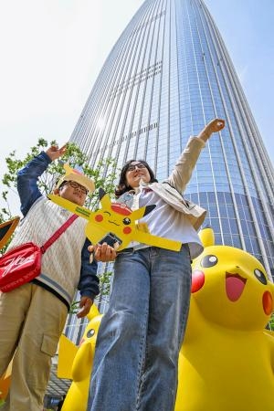 　２６日、ソウルのロッテワールドタワー前に登場したピカチュウの人形と、記念撮影を楽しむ人たち（共同）