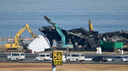 　羽田空港の滑走路で進む日航機の撤去作業。翼部分が切断された＝５日午前