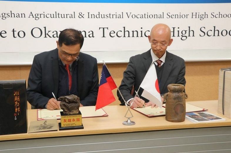調印書に署名する岡山工業高の文谷校長（右）と国立岡山高級農工職業学校の蒋校長