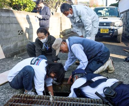　松山市の住宅街で、水路にいるイノシシの捕獲作業にあたる市職員ら＝１日午後