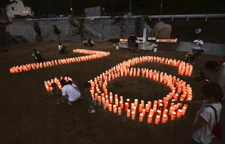 　西日本豪雨から５年となり、被災地の公園に「７・６」の形に並べられた紙灯籠＝６日夜、広島県坂町小屋浦地区