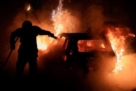 　２日、フランス北部で炎上する車両の消火に当たる消防士（ロイター＝共同）