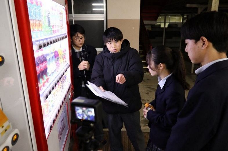 撮影の際、脚本を手に生徒会役員役の生徒（右の２人）に場面の説明をする太田さん（その隣）。左端はカメラと編集担当の野宮さん