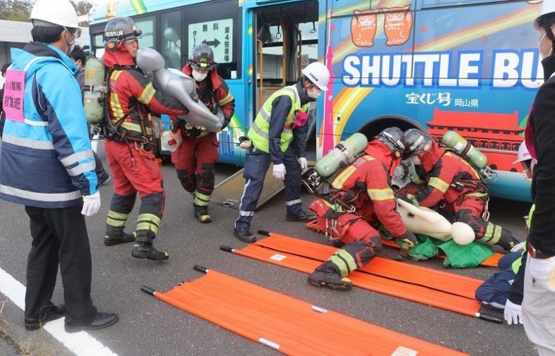 負傷者役の人形を運び出す岡山市消防局の職員ら