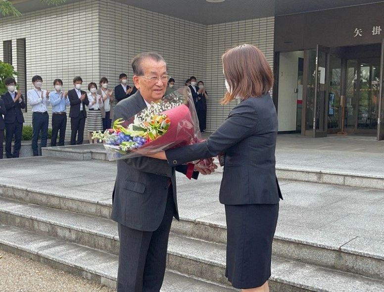 職員から花束を贈られ、退庁する山野町長