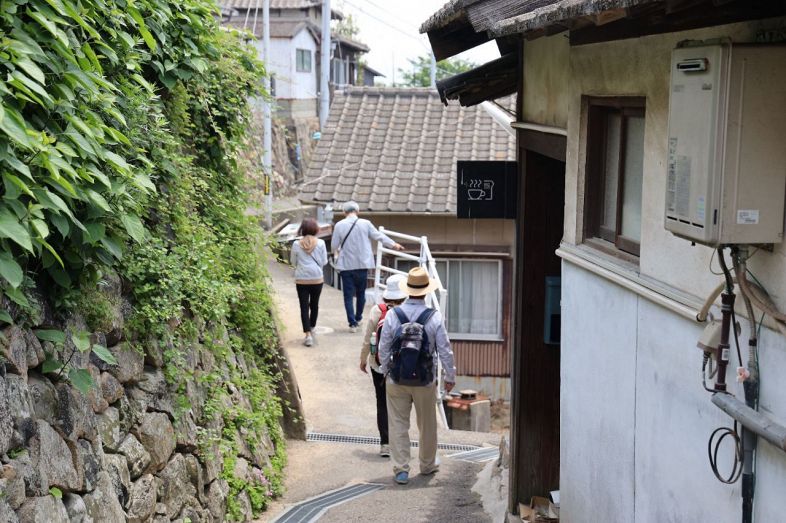 男木島を訪れた観光客。石垣と家並みの間の風情ある道を歩いて回れるのが魅力だ＝２０２２年５月