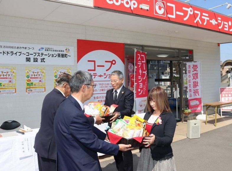 フードドライブ拠点施設の前で倉敷市社協の役員に食品を手渡す平田理事長（左から３人目）ら