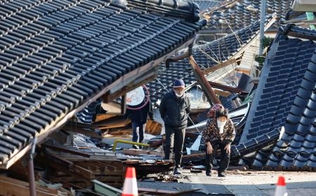　倒壊した家屋の間を歩く女性（８１）ら。全壊した家の様子をいっしょに見に来た家族は「まさかこんなことになるとは」と変わり果てた周囲を見つめていた＝４日午前１０時２６分、石川県珠洲市