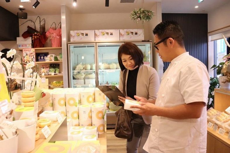 サイト開設に向け、店を取材する西山さん（左）＝浅口市の洋菓子工房ベルジェ