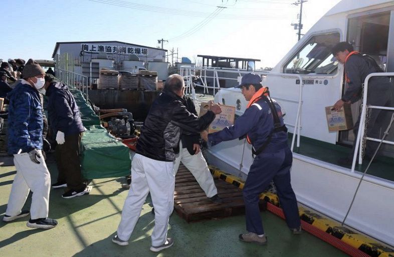 「たましおII」から支援物資を運び出す参加者＝山田港