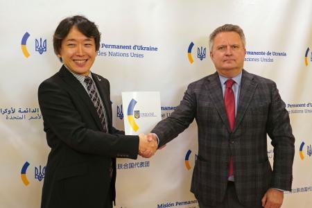 　ウクライナのキスリツァ国連大使（右）と握手する指揮者の伊藤玲阿奈氏＝２０日、米ニューヨーク（共同）