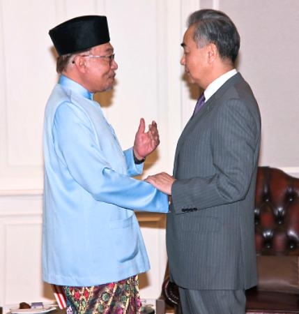　マレーシアのアンワル首相（左）と握手する中国の王毅共産党政治局員兼外相＝１１日、マレーシア・ペナン（中国外務省のホームページより、共同）