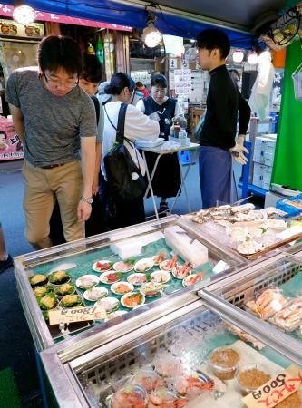 　東京・築地場外市場の鮮魚店で品定めをする買い物客＝２５日午前