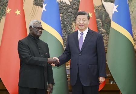 　ソロモン諸島のソガバレ首相（左）と握手する中国の習近平国家主席＝７月１０日、北京の人民大会堂（新華社＝共同）