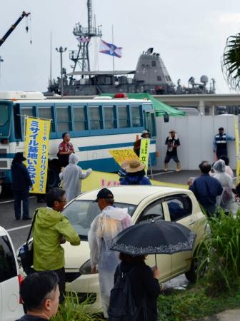 　米海軍の掃海艦「パイオニア」（奥）の入港に反対し、石垣港周辺に集まった人たち＝７日午前、沖縄県・石垣島