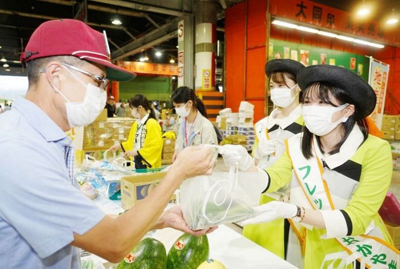 岡山県産青果物の袋詰めを市場関係者に手渡すフレッシュおかやまのメンバー（右）