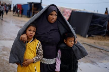 　パレスチナ自治区ガザ南部ラファで、雨の中を歩く避難民＝１３日（ロイター＝共同）