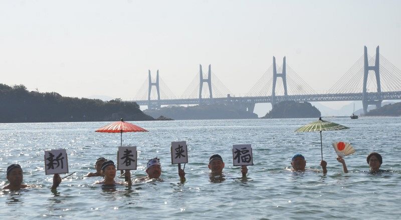 瀬戸大橋を背に「新春来福」　倉敷 神伝流の初泳ぎ、水上で揮毫