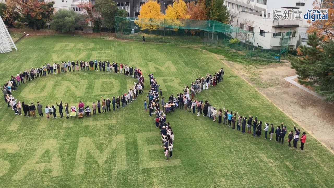 芝生アートに「ＯＫ」の人文字　岡山芸術交流 ２００人で公式ロゴ